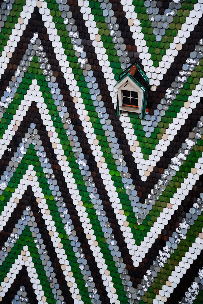 Vibrant chevron tiled roof with a wooden dormer window in artistic style.